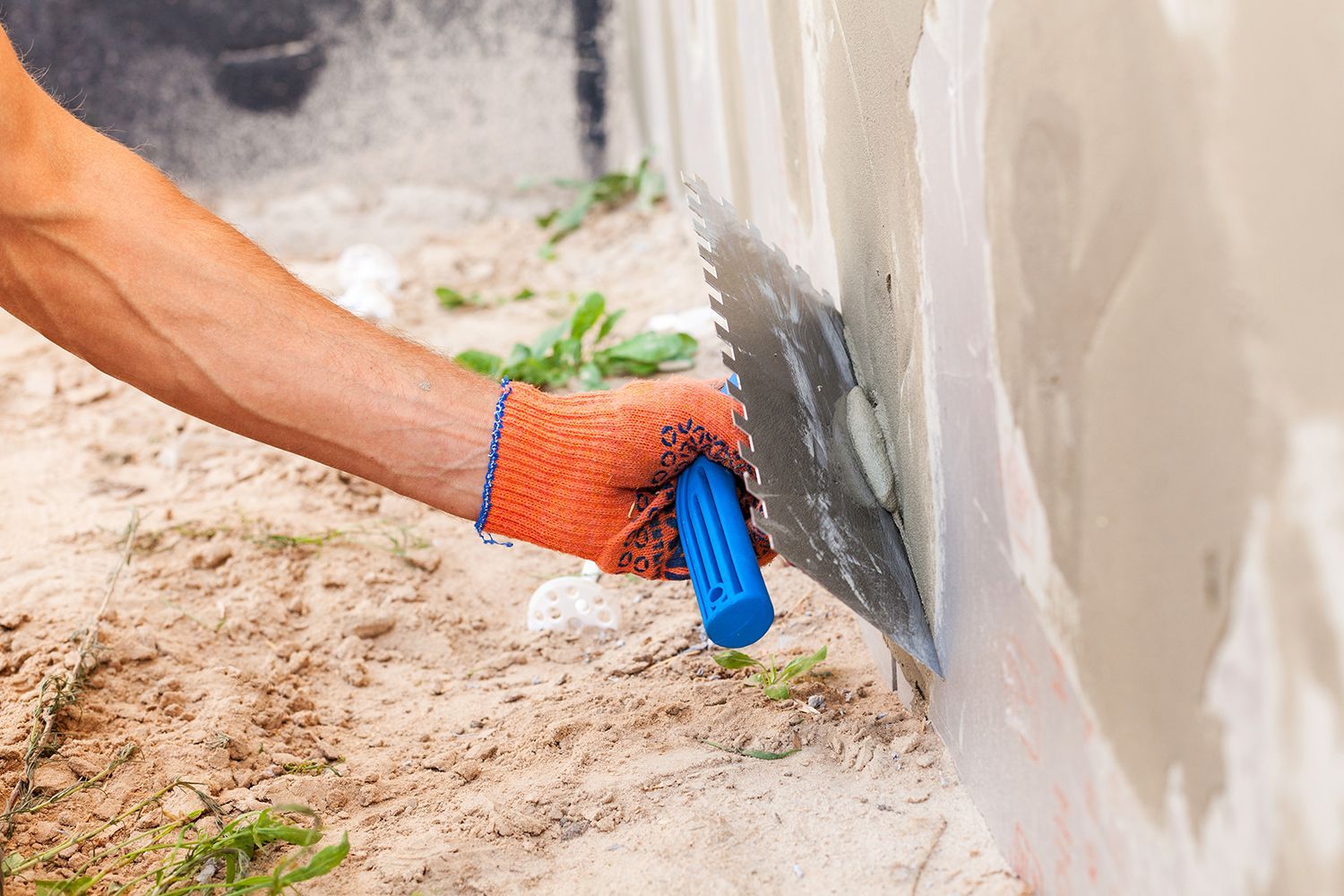 Construction worker plastering a wall and house foundation with trowel. Construction worker plastering a wall and house foundation with trowel.