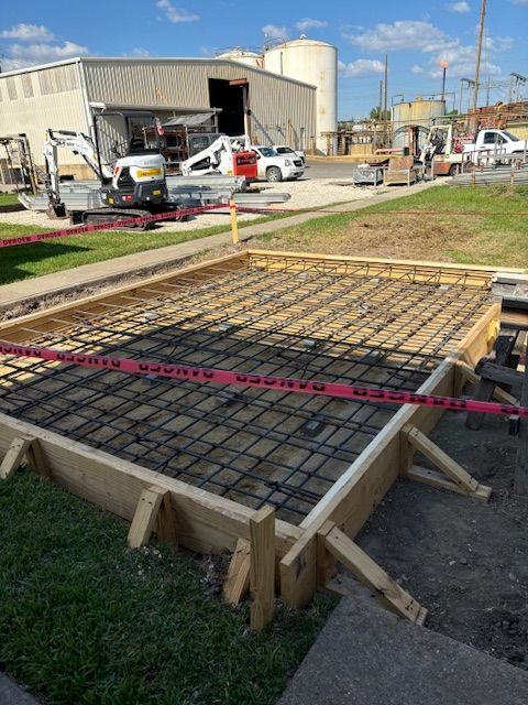 Concrete form with rebar, caution tape, and construction equipment in a work area.