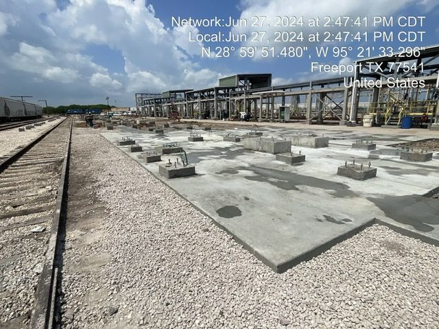Construction site with concrete foundations and rail tracks, Freeport, TX. Date/time stamp.