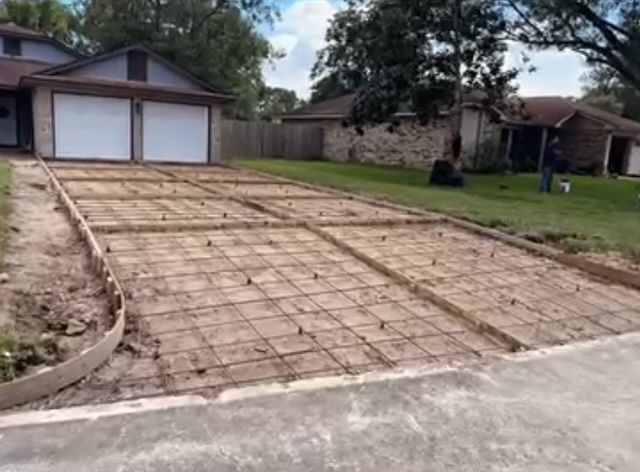 Driveway construction site: Wire mesh laid for new concrete driveway, garage in background.