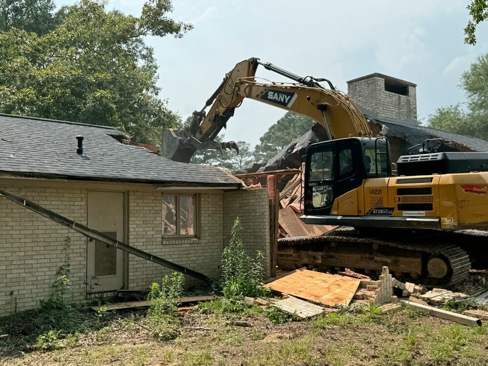 A large excavator demolishing a house on a sunny day.