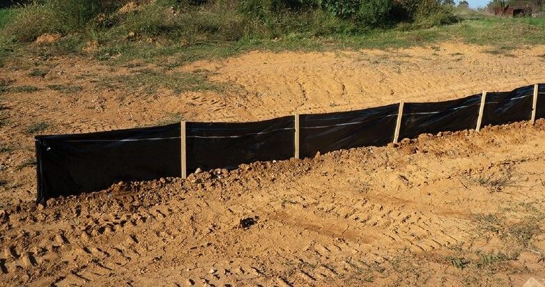 Black silt fence installed along a dirt embankment, preventing erosion.