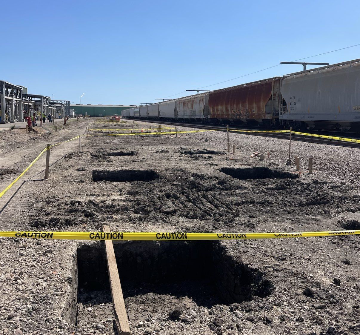 Excavator digging a trench in a field on an overcast day.