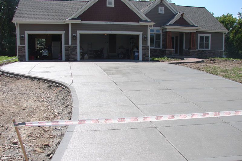 Concrete driveway leading to a two-car garage of a house. Red and white caution tape blocks access.
