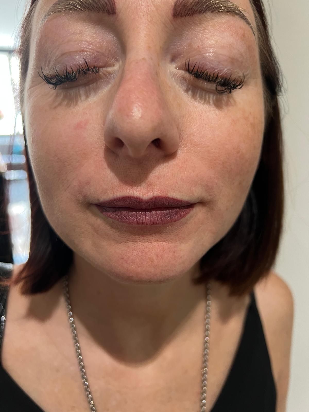 Eine Nahaufnahme des Gesichts einer Frau mit geschlossenen Augen und roten Lippen.