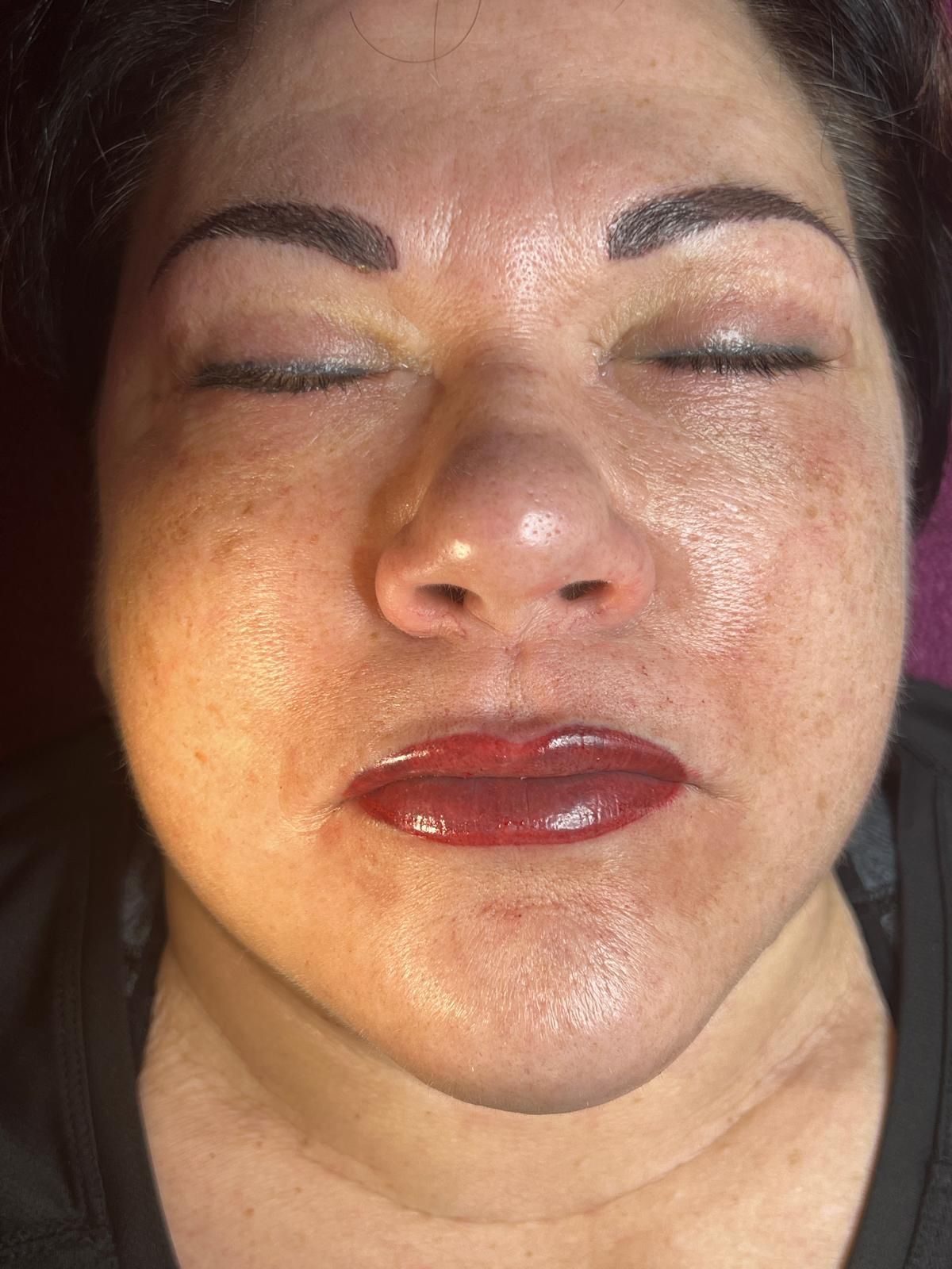 Eine Nahaufnahme des Gesichts einer Frau mit geschlossenen Augen und roten Lippen.