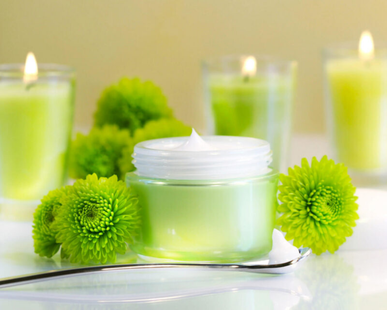 Ein Glas Sahne ist von grünen Blumen und Kerzen umgeben