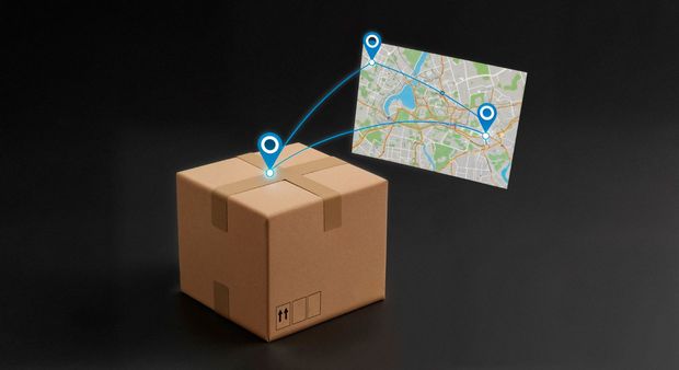 Una caja de cartón marrón sobre una superficie negra, con una proyección de mapa digital