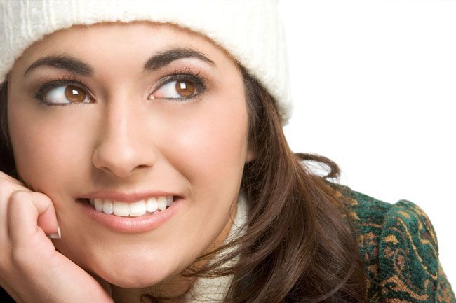 a woman wearing a white hat and scarf is smiling .