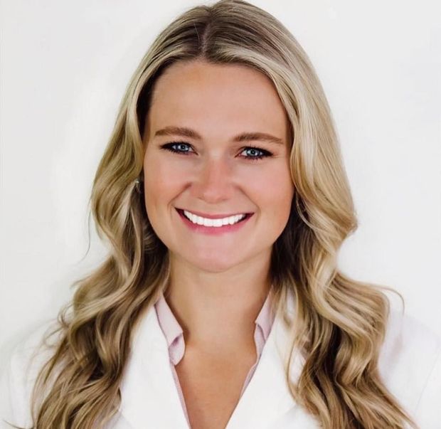 Smiling blonde woman in a white blouse against a light background
