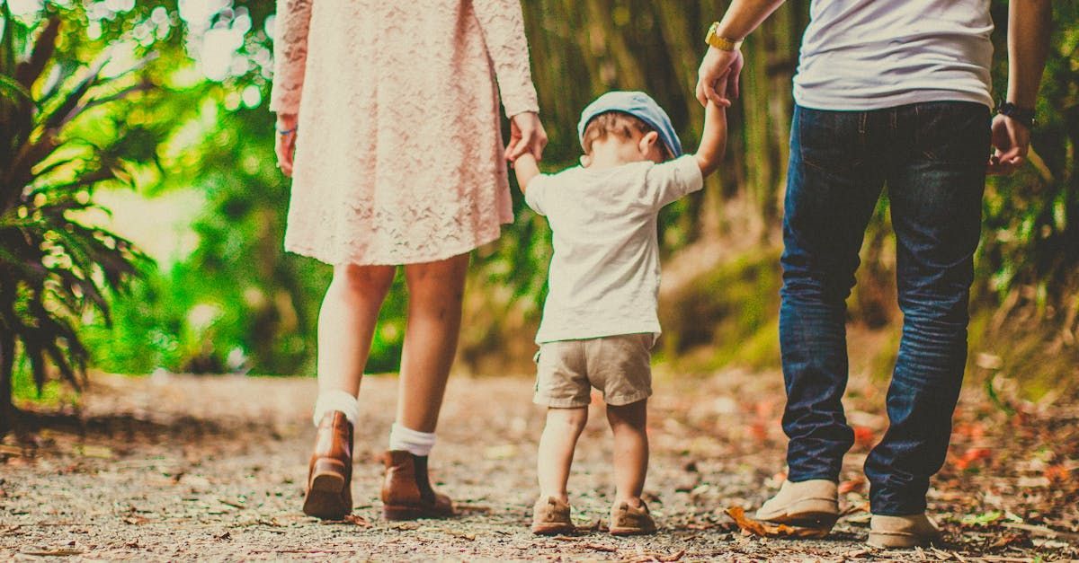 A family is walking down a dirt road holding hands.