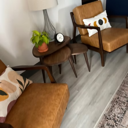 A living room with two chairs and a table with a clock on it