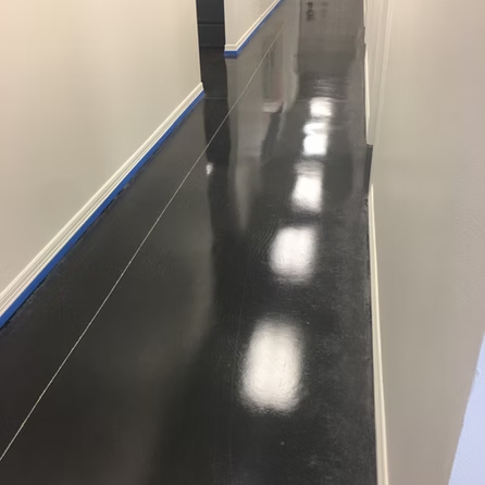 A hallway with a black floor and white walls.