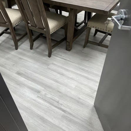 A dining room table and chairs are sitting on a white wooden floor.