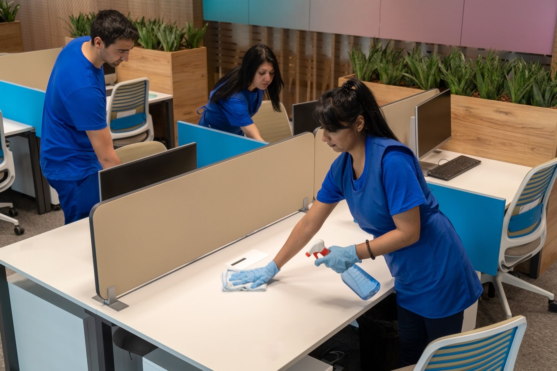 A group of people are cleaning desks in an office.