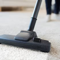 A person is using a vacuum cleaner to clean a carpet.