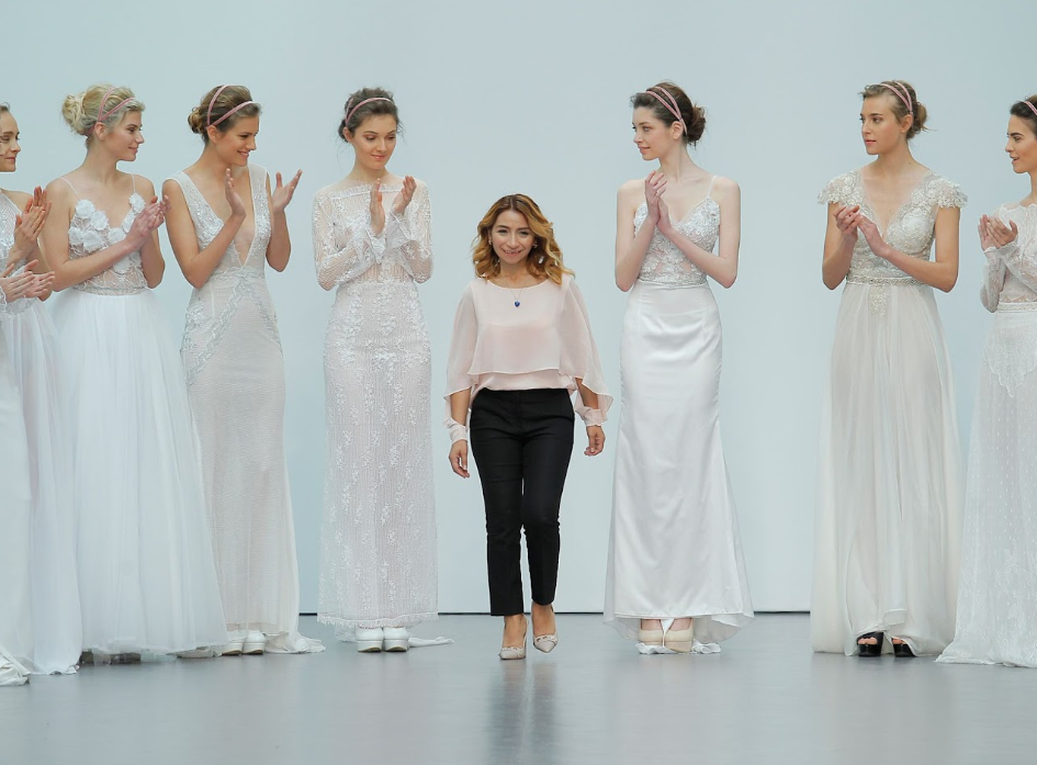 Diseñador de moda en la pasarela con modelos vestidas de novia, aplaudiendo.
