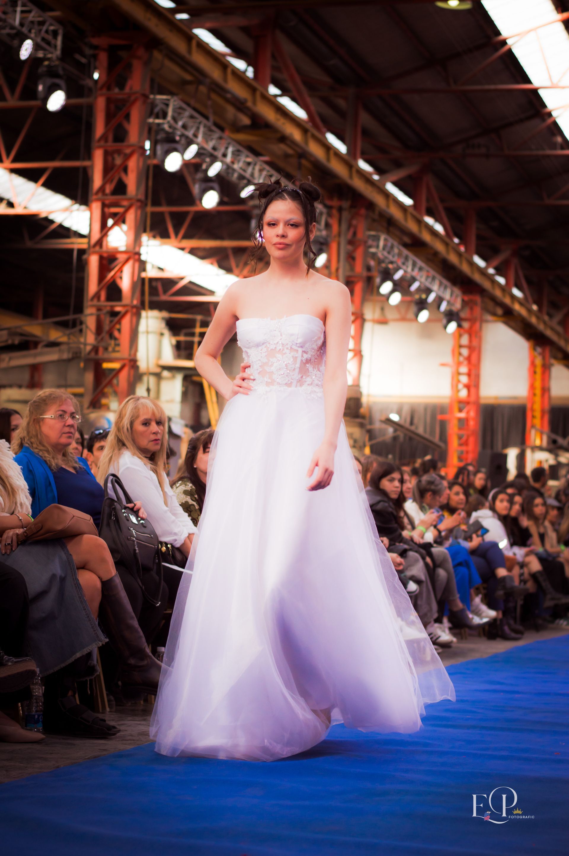 Mujer con un vestido de noche dorado y brillante, con un pronunciado escote, posando en un estudio.