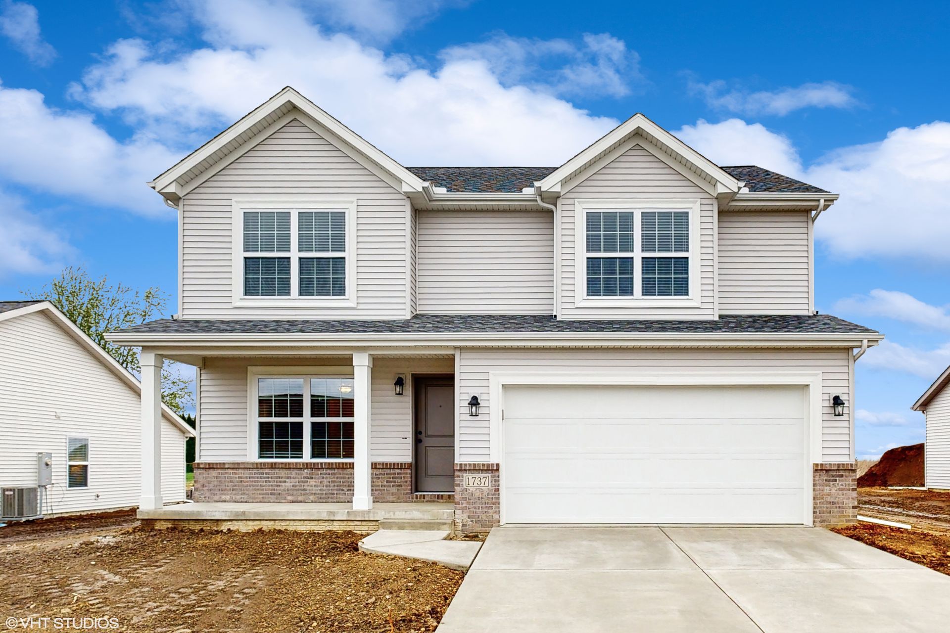 The front of a white house with a garage and a blue sky in the background.