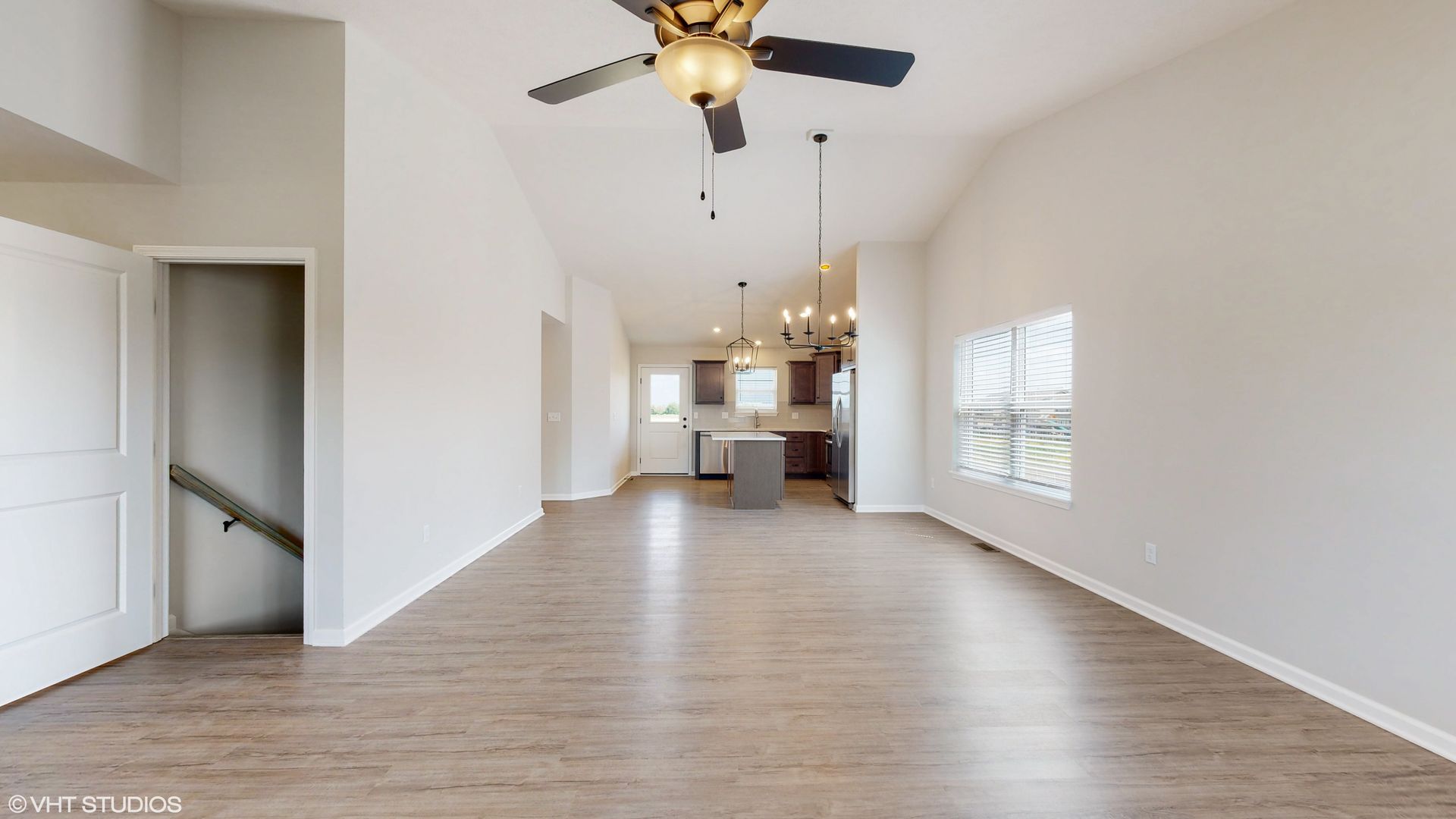 An empty living room with hardwood floors and a ceiling fan.