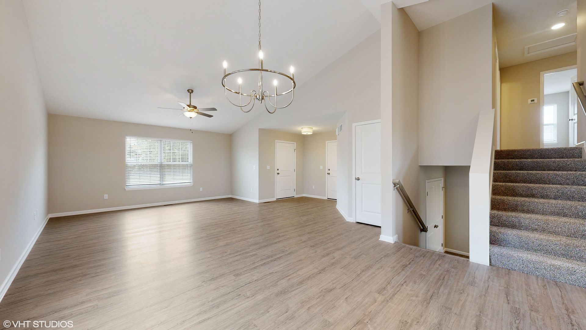 An empty living room with hardwood floors and stairs in a house.