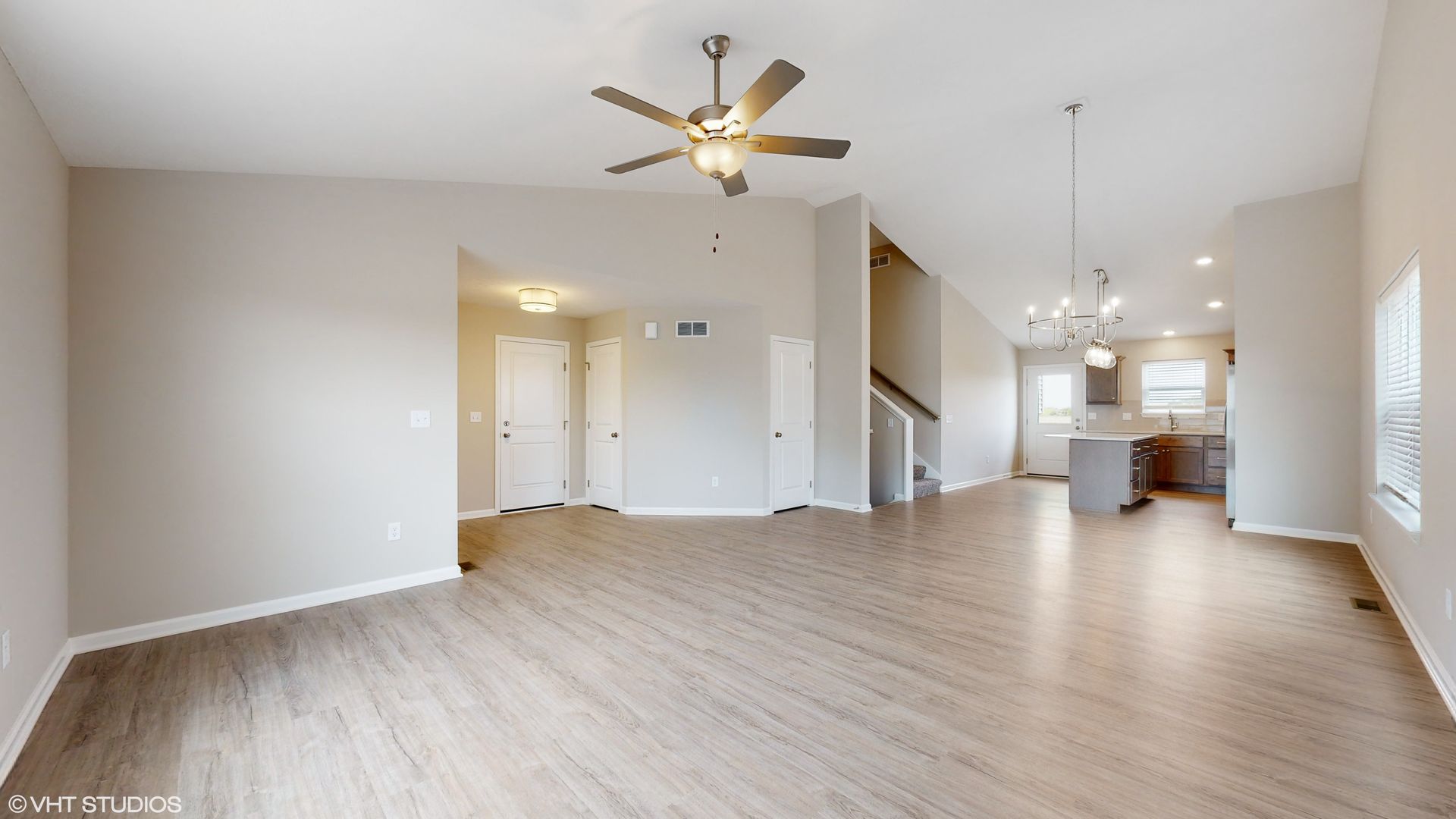 An empty living room with hardwood floors and a ceiling fan.