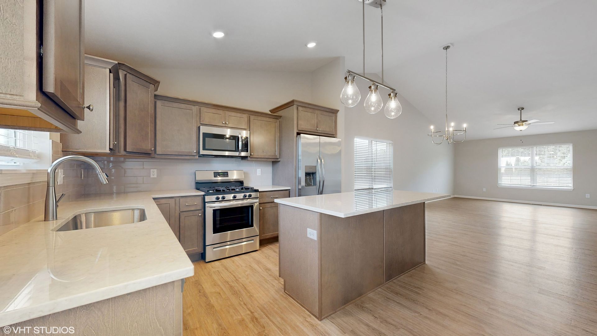 A kitchen with stainless steel appliances and a large island in the middle of the room.