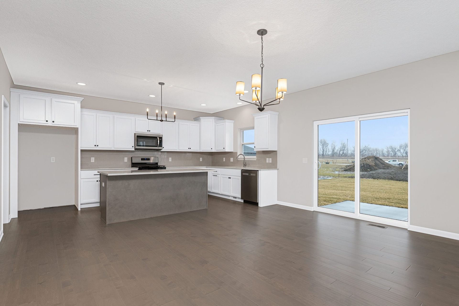An empty kitchen with sliding glass doors and a chandelier hanging from the ceiling.