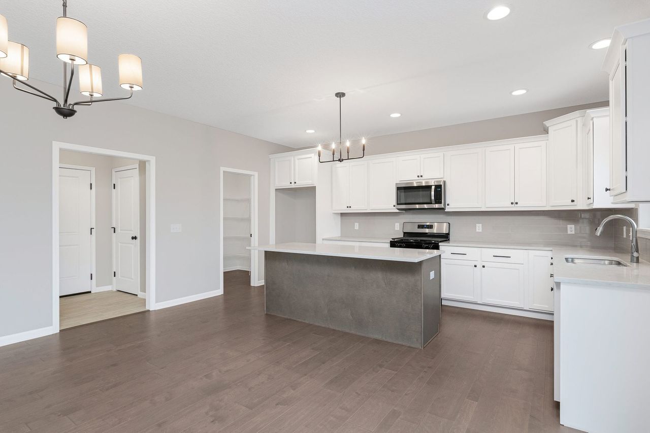 An empty kitchen with white cabinets and a large island.