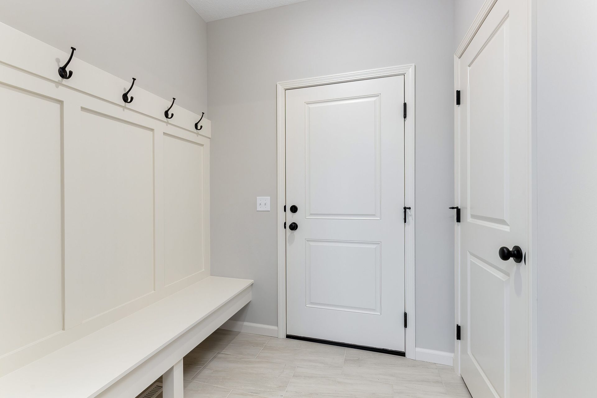 A hallway with a white bench and a white door.