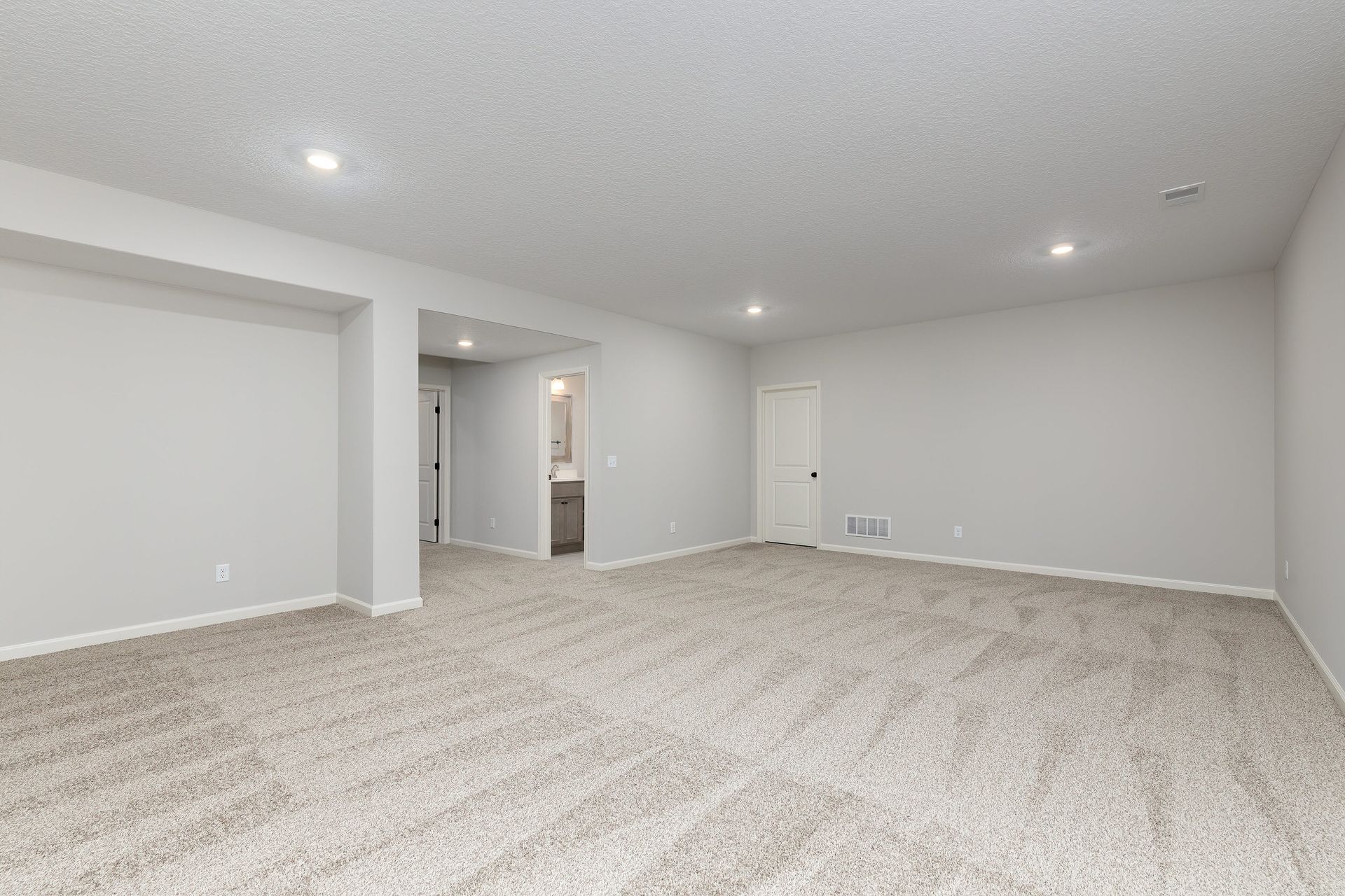 An empty basement with a carpeted floor and white walls.
