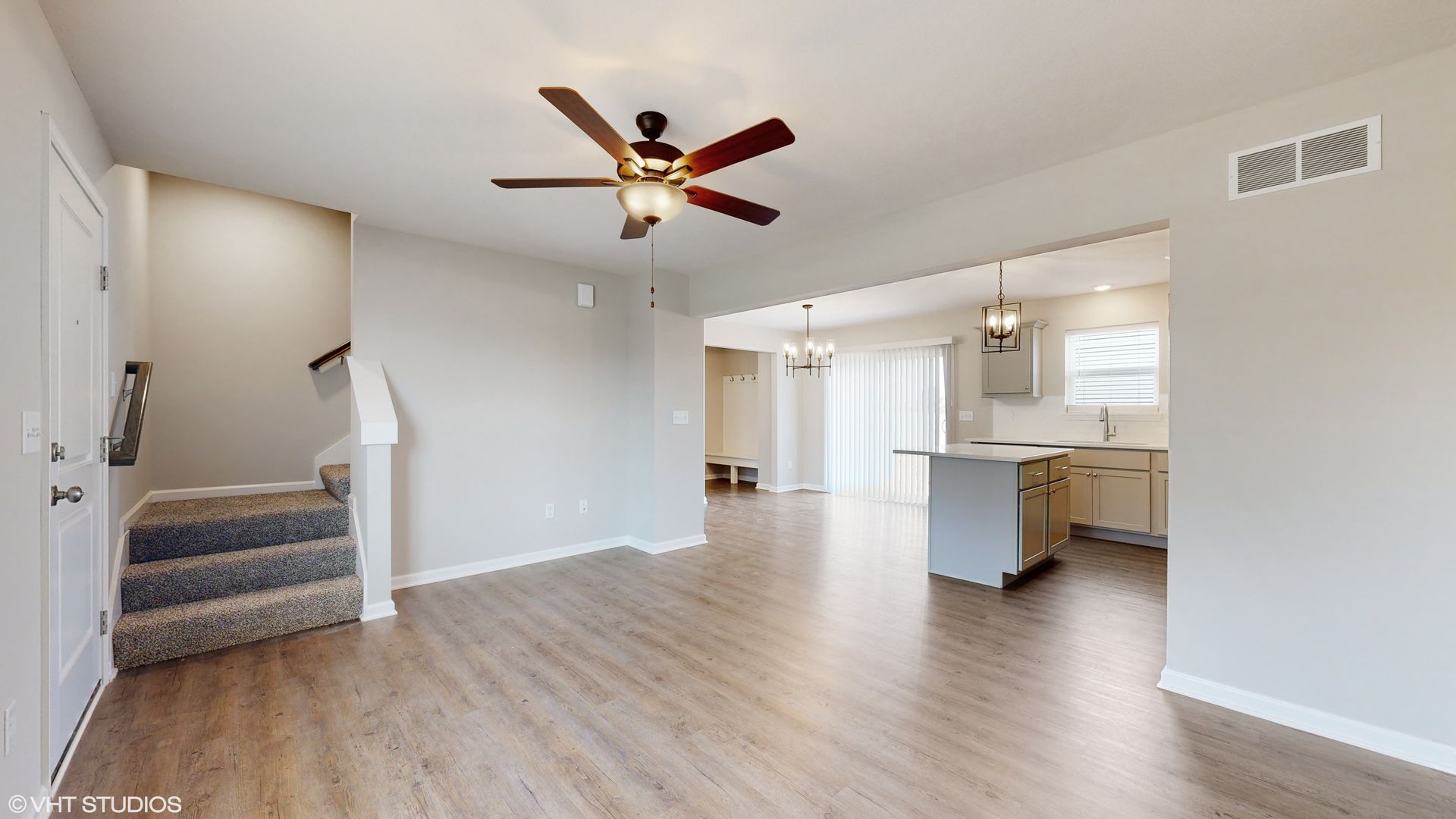 An empty living room with hardwood floors and a ceiling fan.