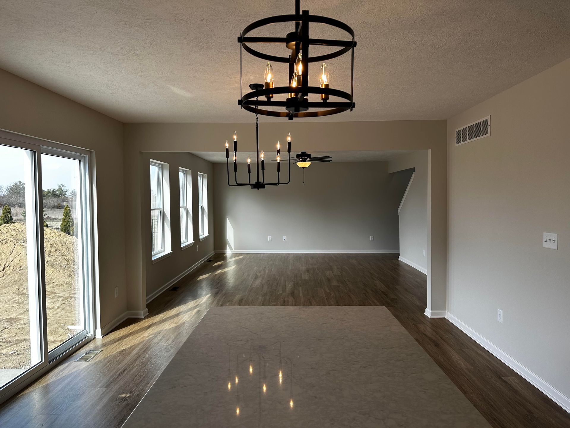 An empty living room with a chandelier hanging from the ceiling