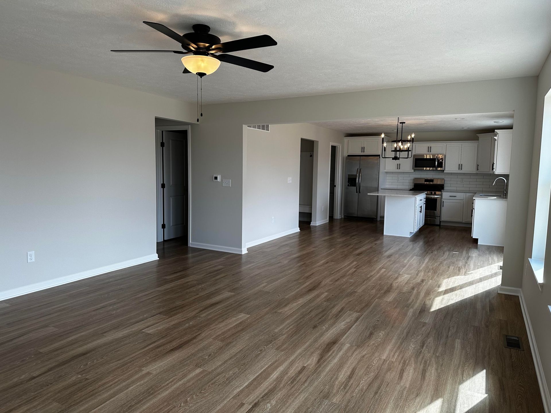 An empty living room with hardwood floors and a ceiling fan