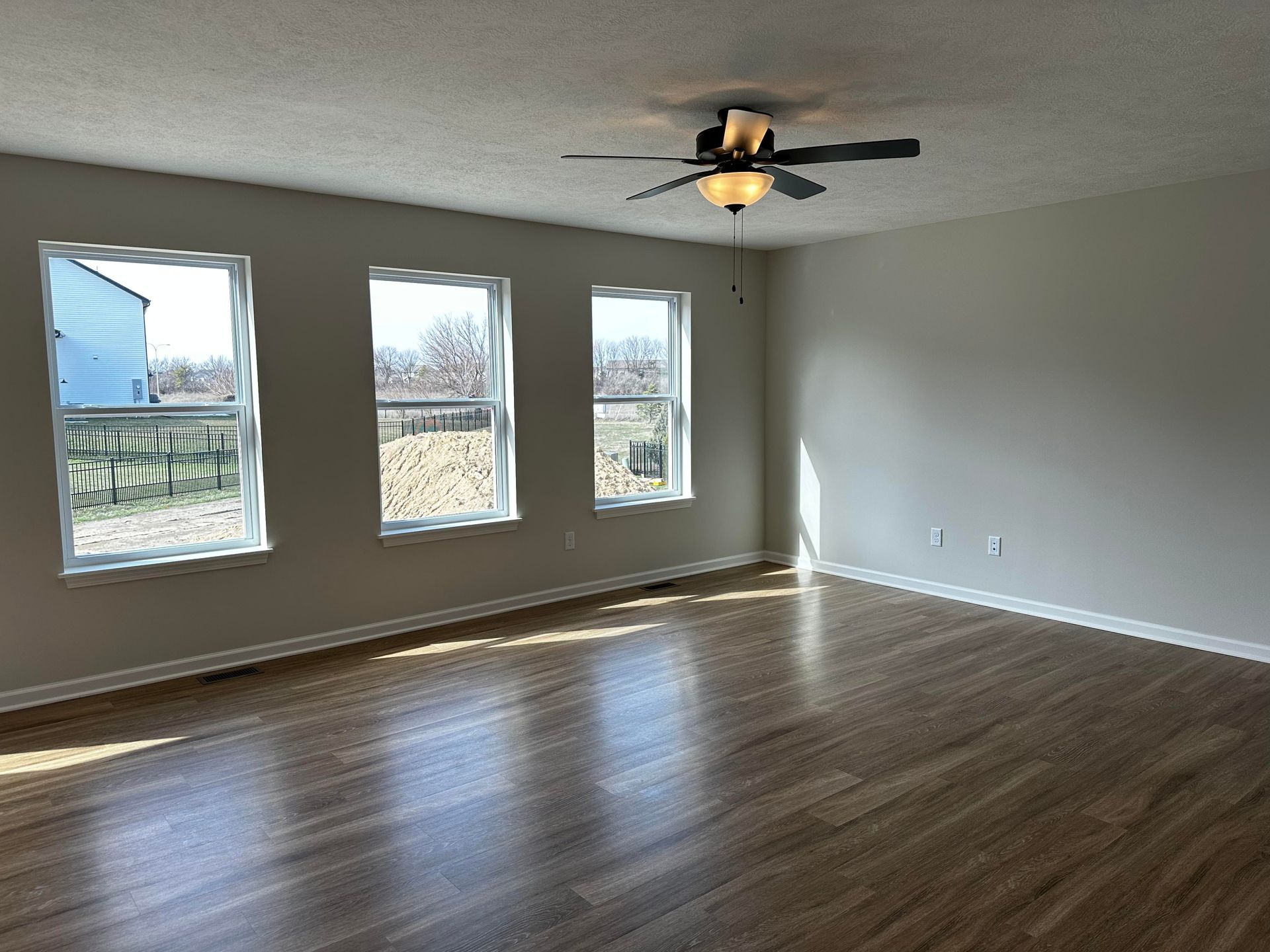 An empty living room with hardwood floors and a ceiling fan.