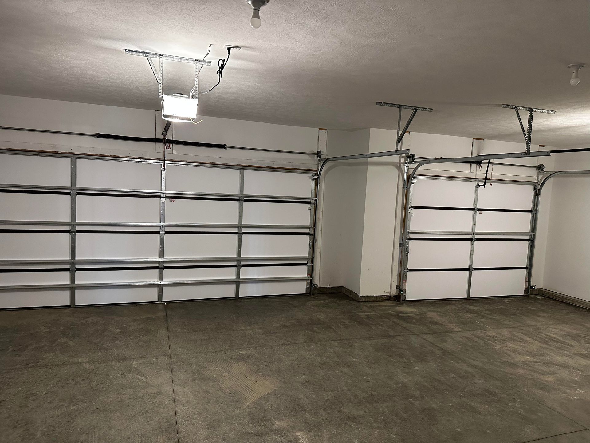 An empty garage with two garage doors and a light on the ceiling.