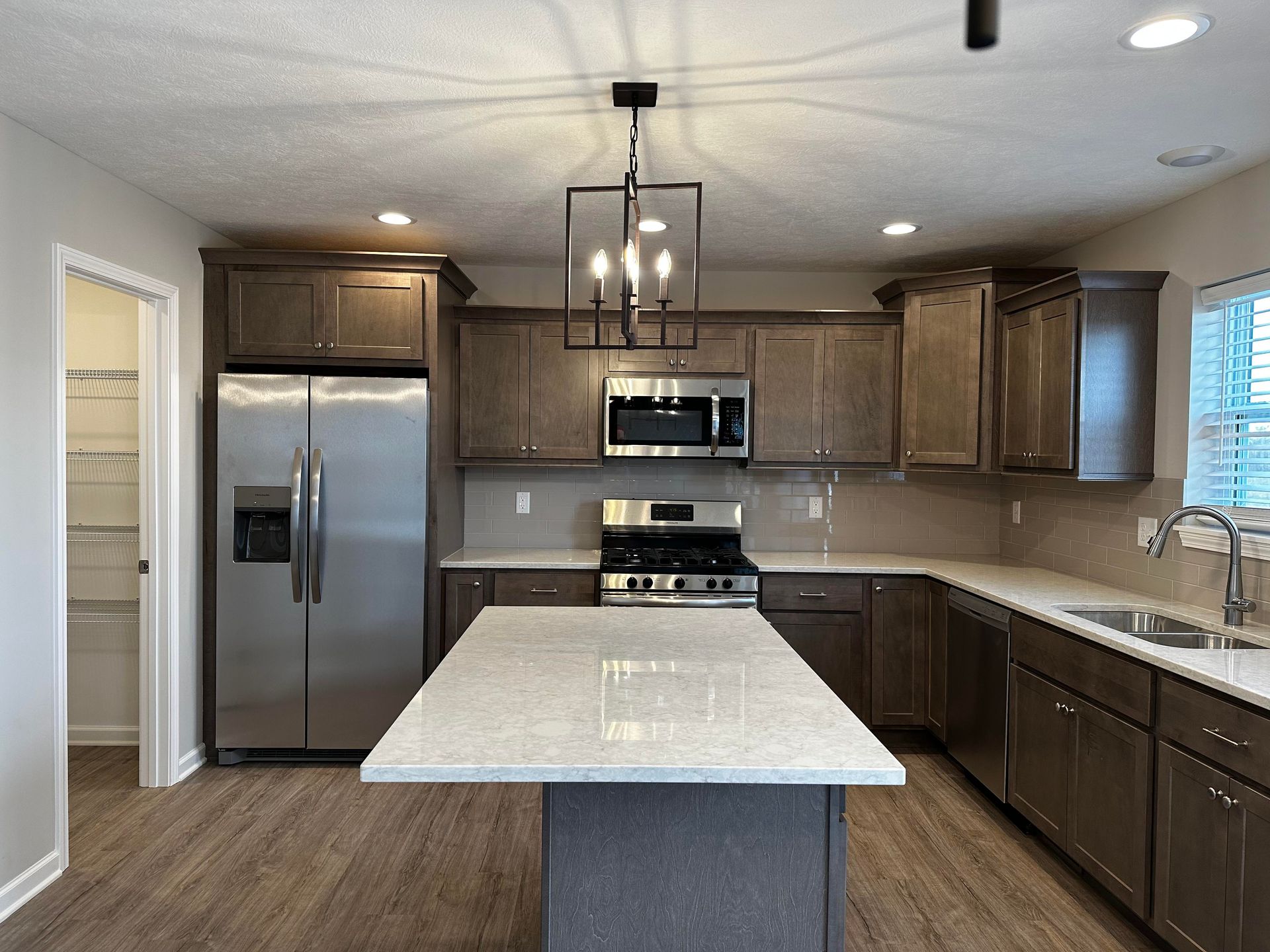 A kitchen with stainless steel appliances and a large island in the middle.