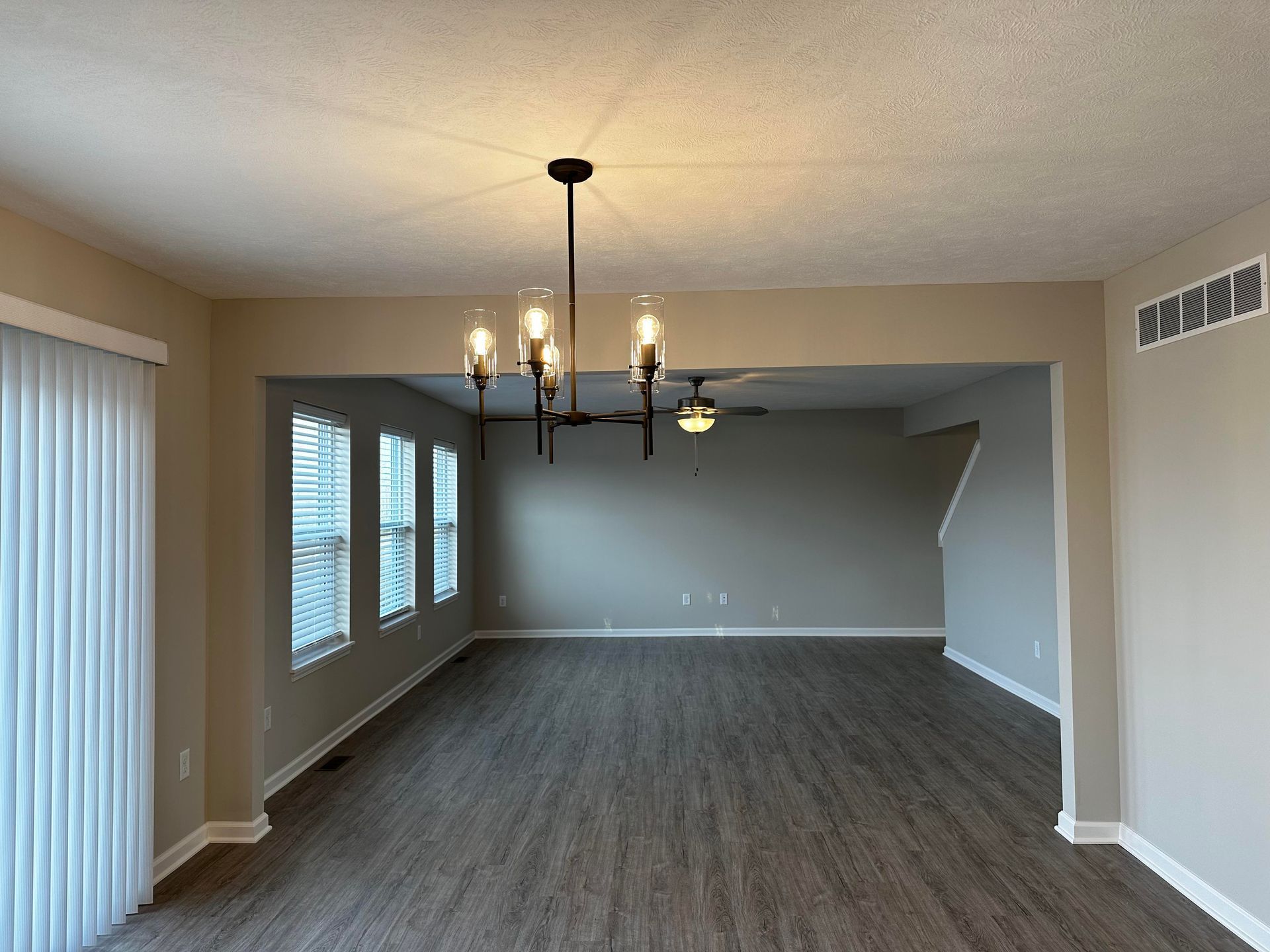An empty living room with a chandelier and a ceiling fan.