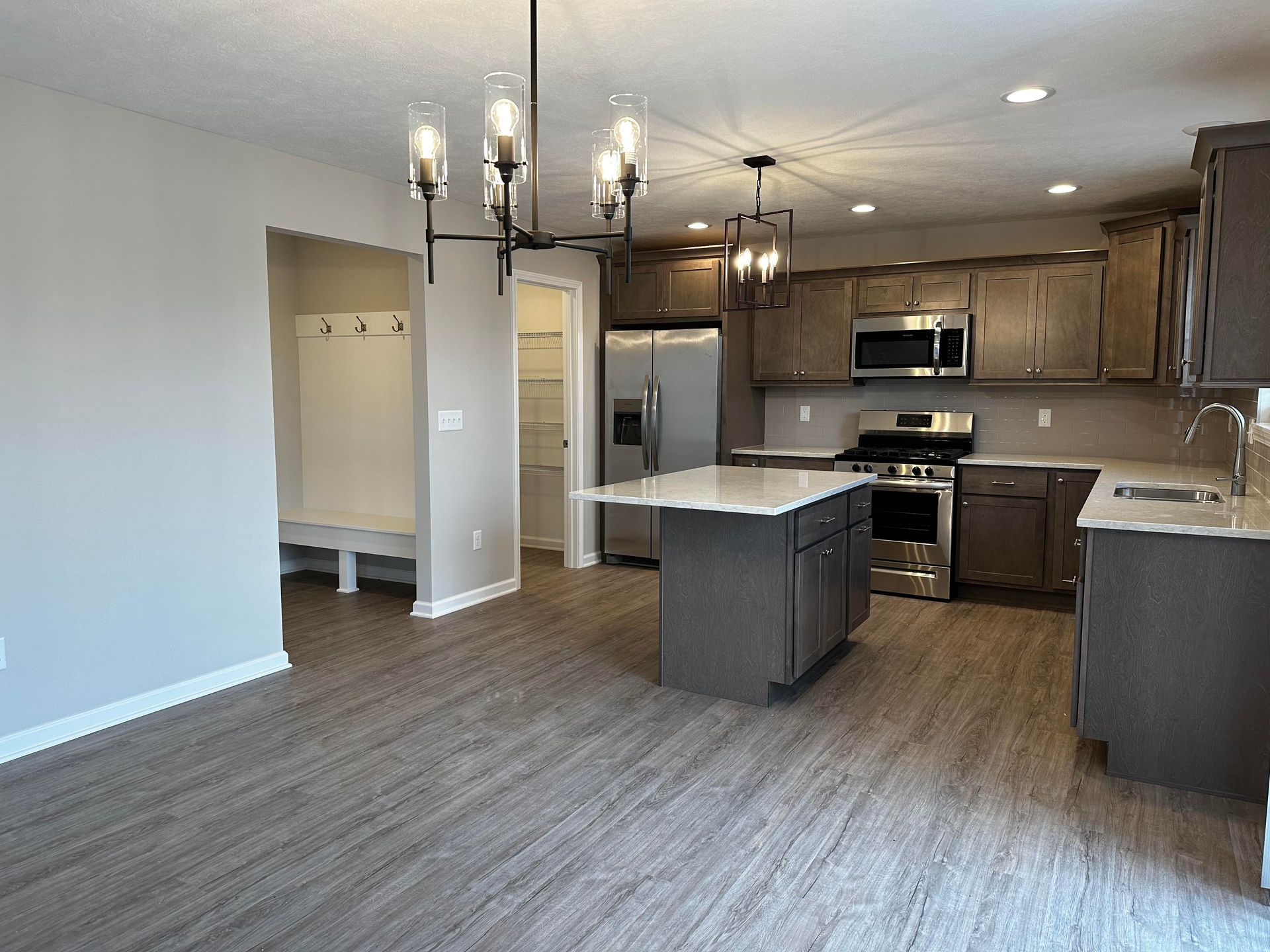 An empty kitchen with stainless steel appliances and a large island.