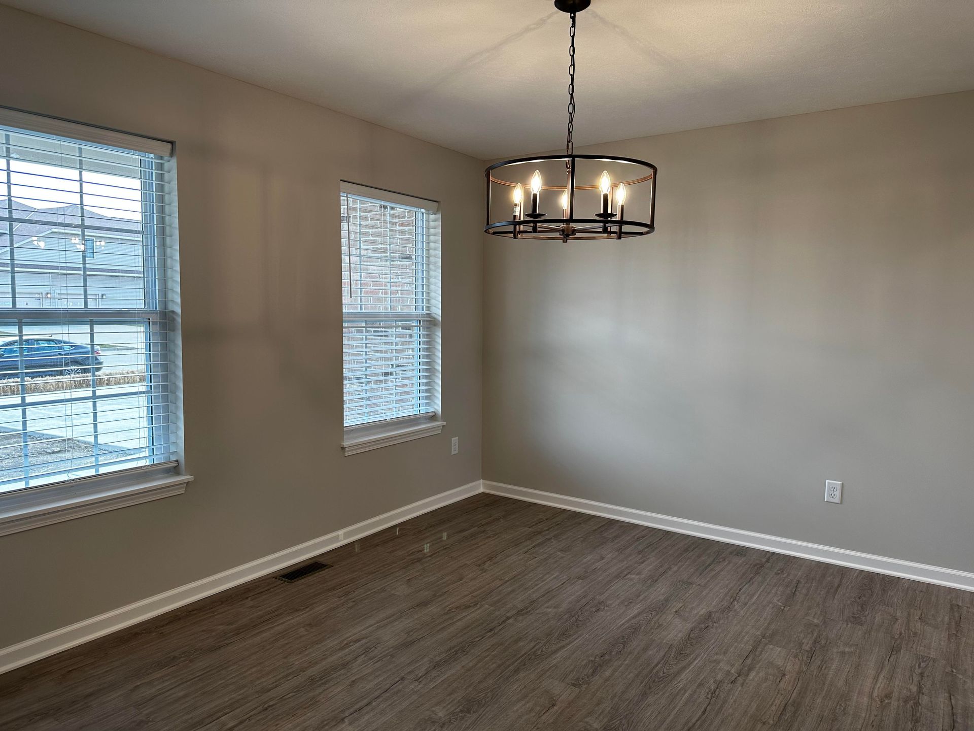 An empty dining room with a chandelier hanging from the ceiling.