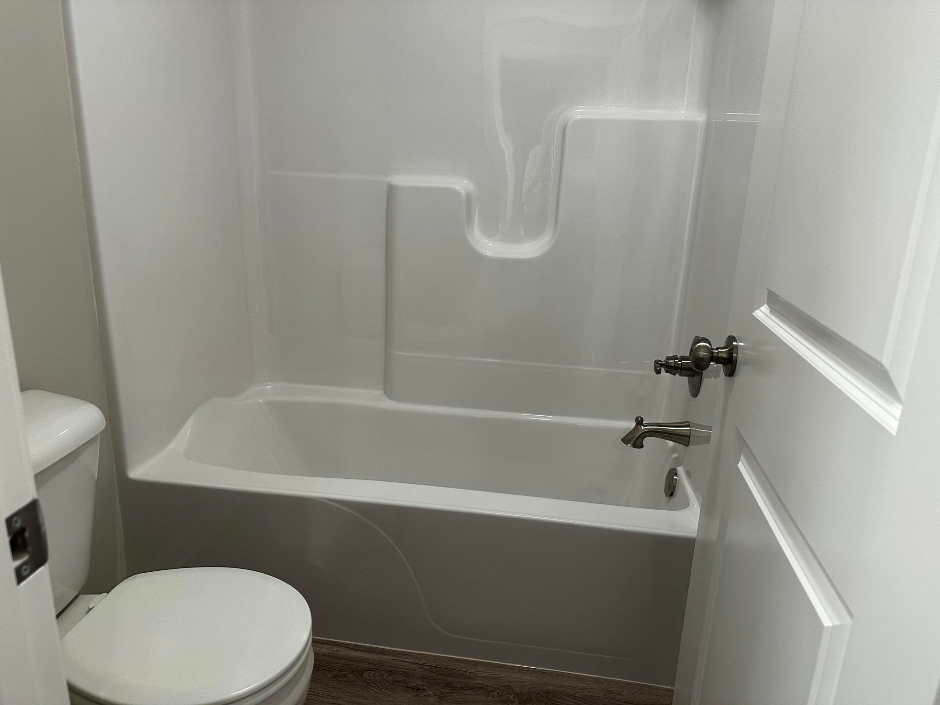 A bathroom with a toilet , tub and shower.