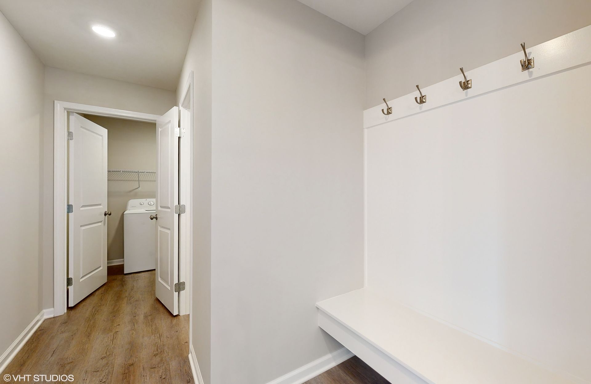 A laundry room with a washer and dryer and a bench.