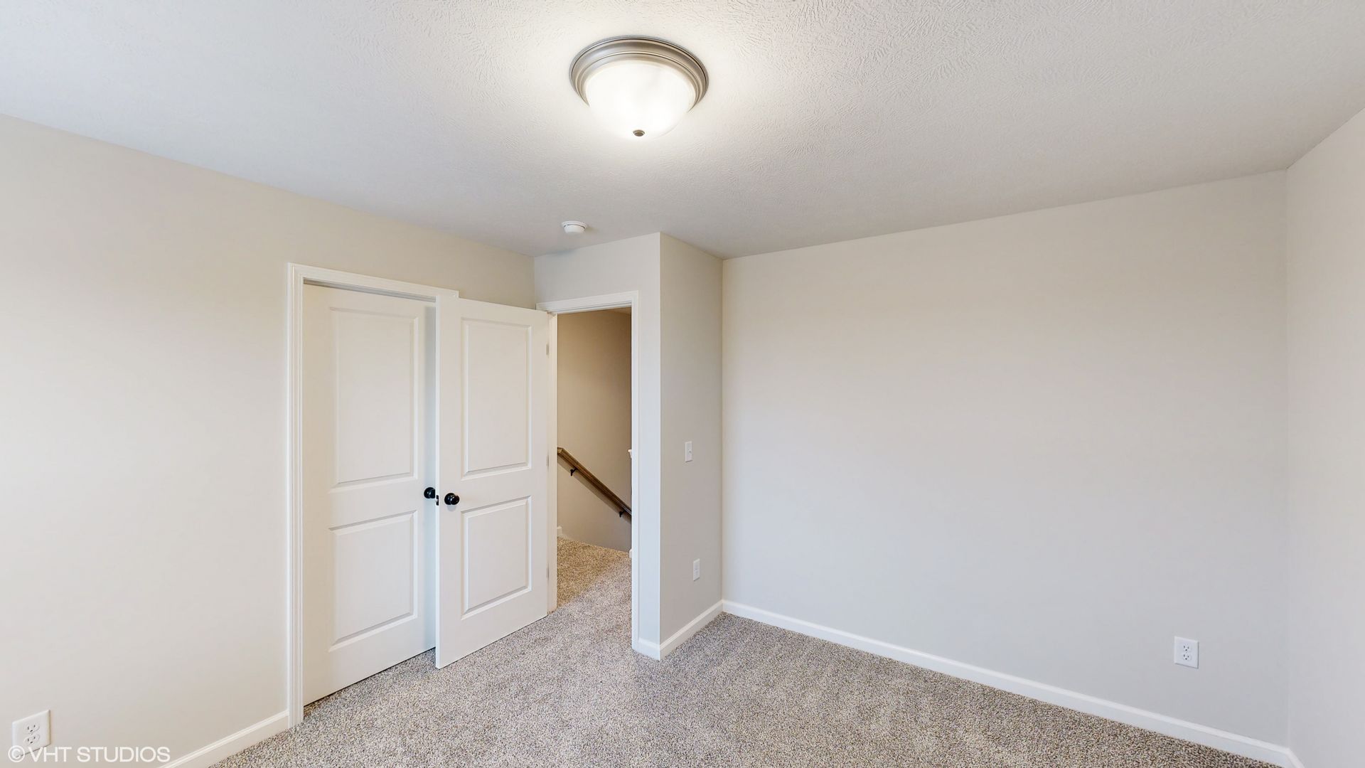 An empty bedroom with a staircase leading to the second floor.