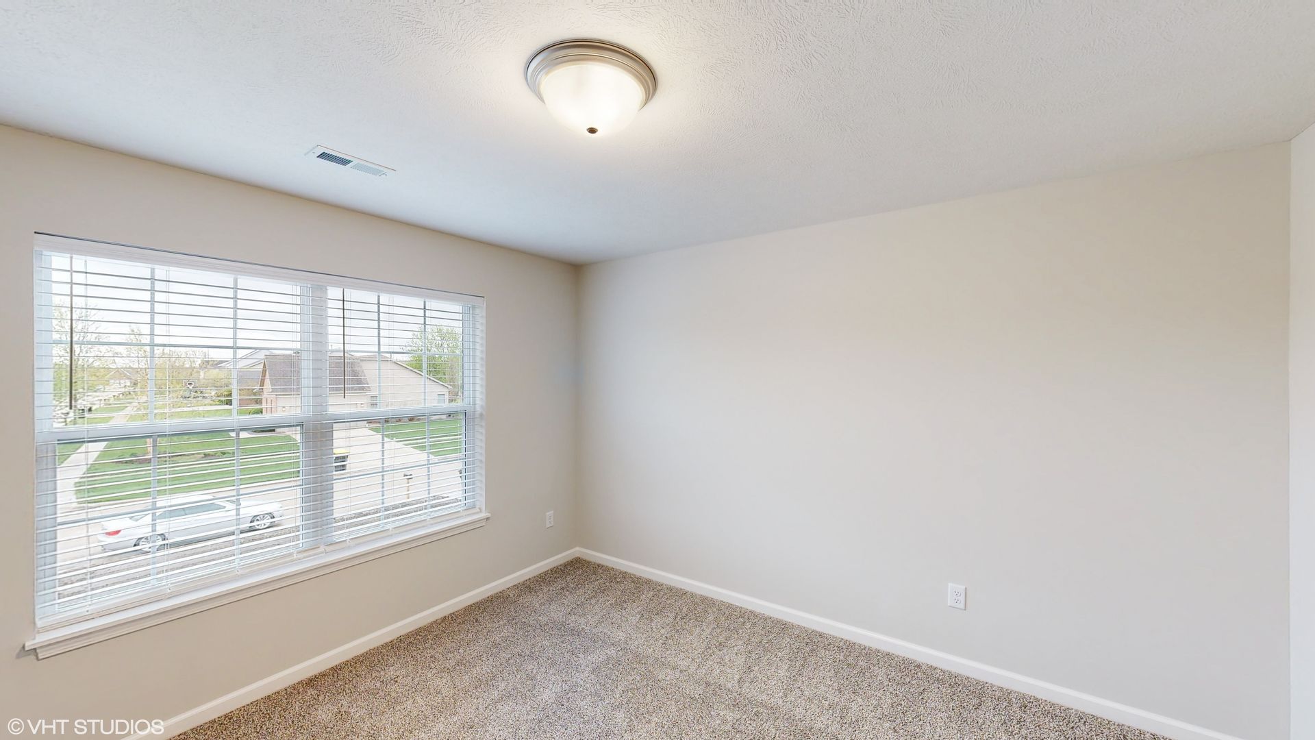An empty bedroom with two windows and a ceiling light.