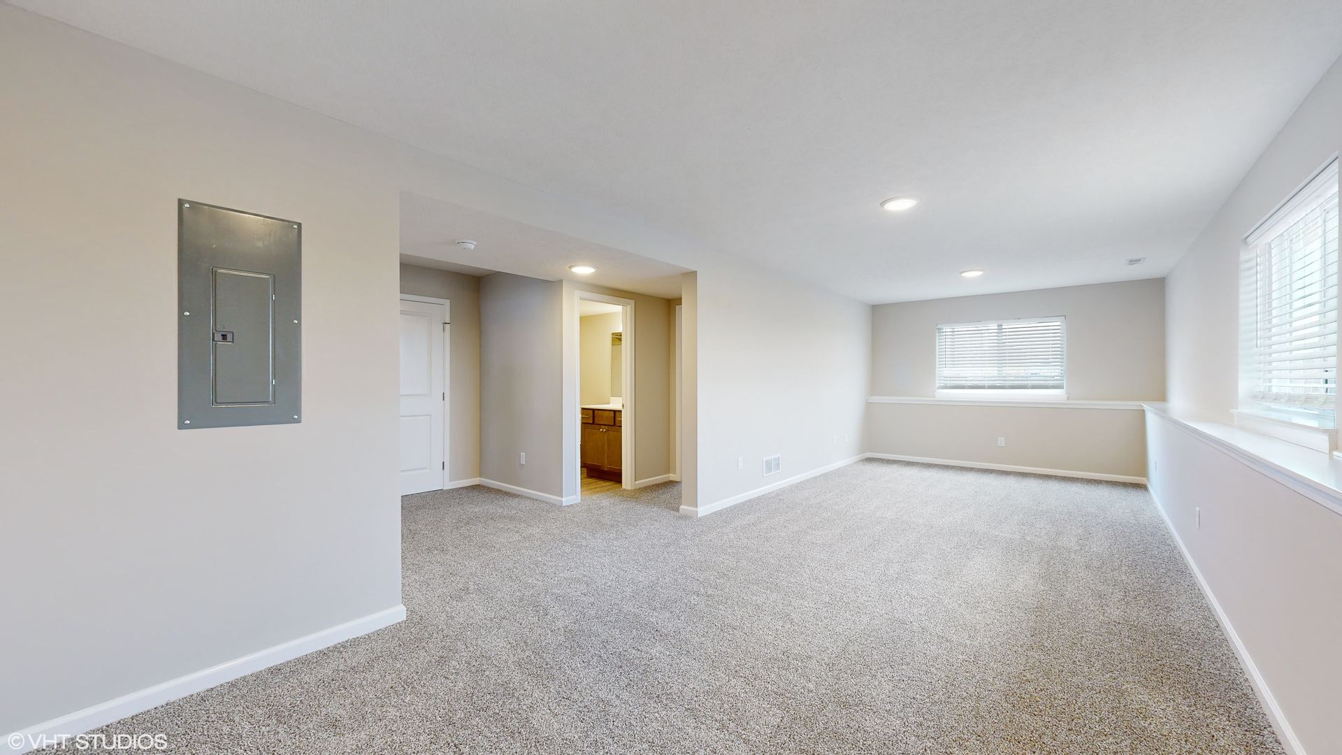 A large empty room with a carpeted floor and a window.