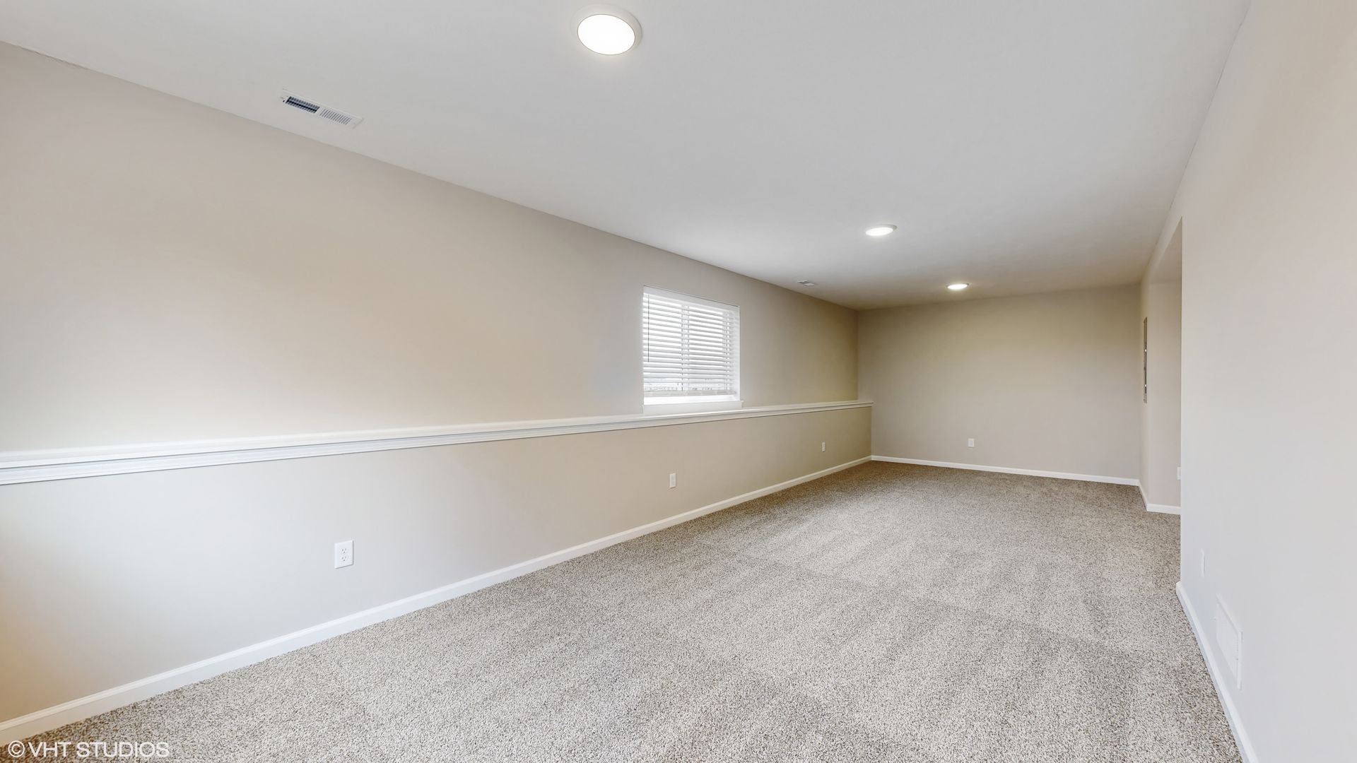 An empty room with a carpeted floor and a window.