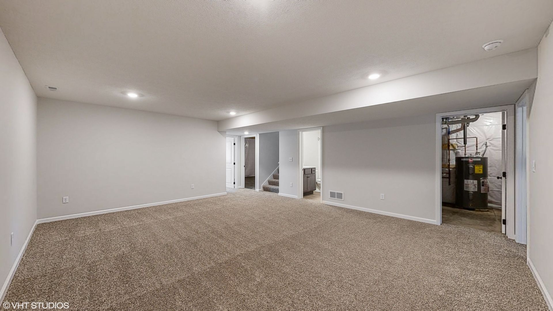 An empty basement with a carpeted floor and white walls.