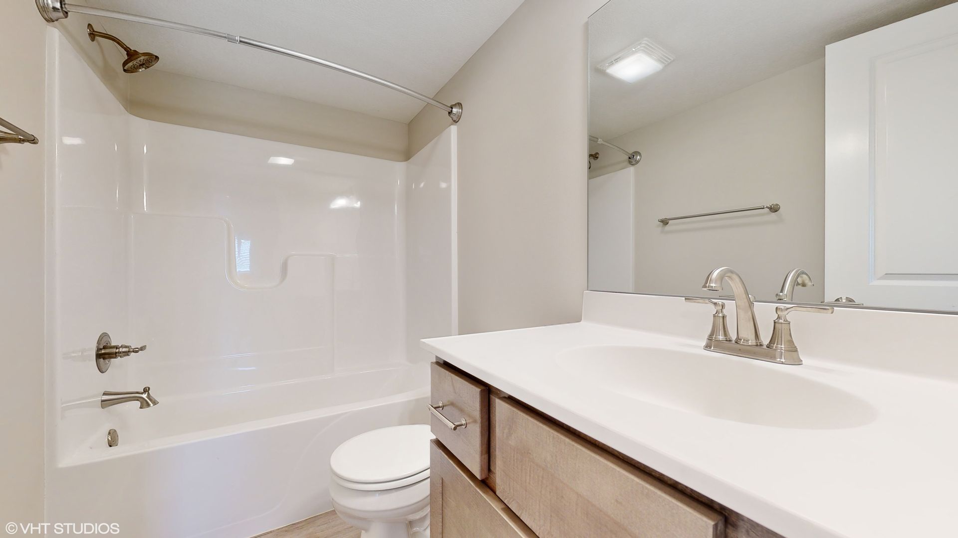 A bathroom with a sink , toilet , shower and mirror.