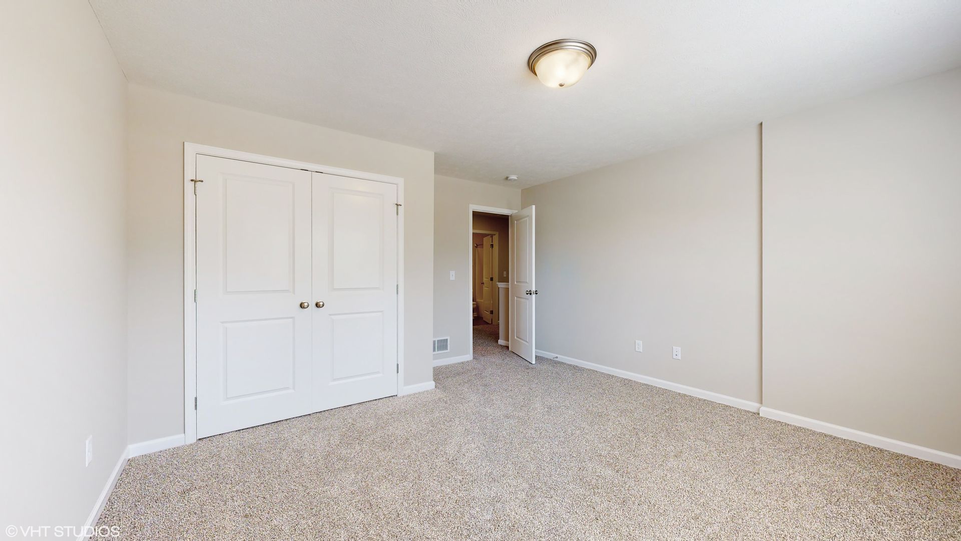 An empty bedroom with a carpeted floor and a closet.