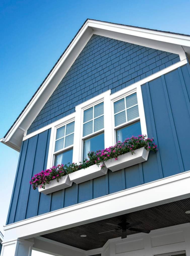 A blue house with purple flowers in a window box